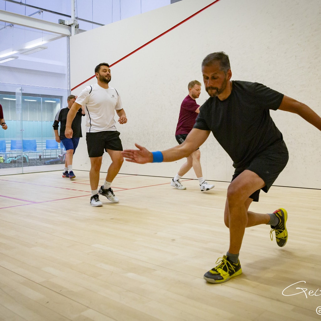 Squash coach showing technique to a group on the court.